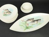 several plates and bowls with fish painted on them on a black surface