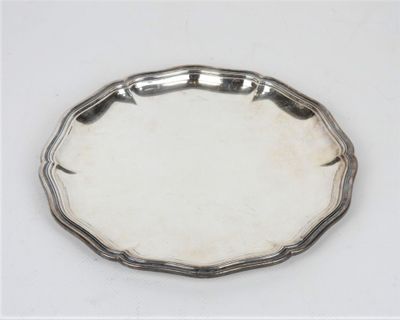 une assiette ancienne en argent, avec un bord décoratif sur une surface blanche