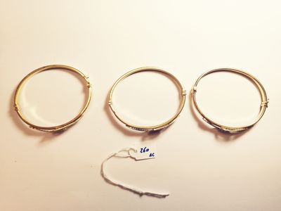 three gold rings and a pair of scissors on a white surface
