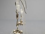 une paire de boucles d'oreilles en argent posée sur un socle en acrylique transparent