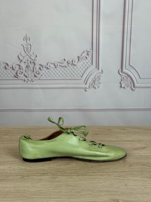 pair of green shoes sitting on a wooden table in front of a wall