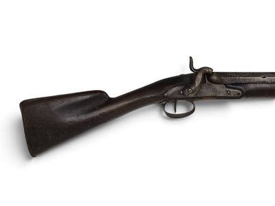 un vieux fusil exposé sur une surface blanche
