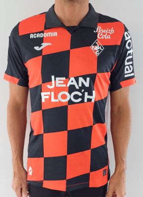 Cet homme porte un t-shirt rouge et noir et un pantalon noir.