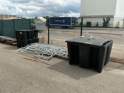 a black trash can sitting next to a black trash can on the side of the road