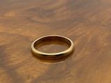 a close up of a gold wedding ring on a wooden table