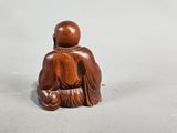 an image of a wooden statue of a person sitting on a chair