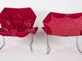 two red chairs with folded fabric on them against a white background