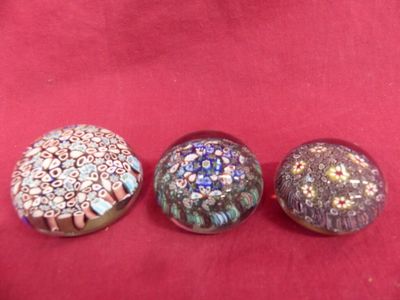 three glass buttons sitting on top of a red cloth