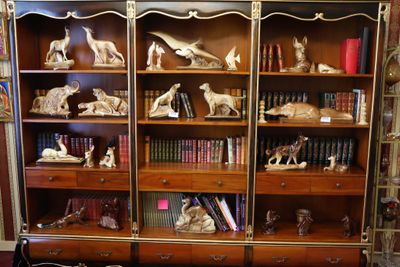 une bibliothèque sur laquelle sont posés de nombreux livres et des statues
