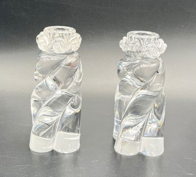 une paire de bougeoirs en verre transparent posés sur une surface brillante