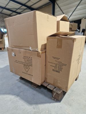 des cartons empilés sur une palette dans un entrepôt, avec un homme à l'arrière-plan