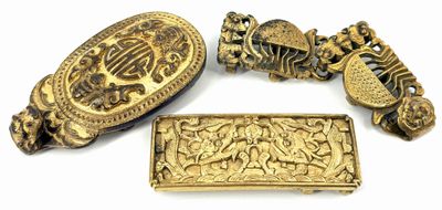 four pieces of gold jewelry on a white surface