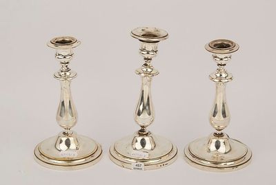 three silver candlesticks are sitting on a white surface