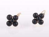 une paire de boucles d'oreilles avec des perles noires sur fond blanc