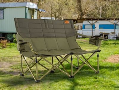 a lawn chair that is in the grass near a trailer