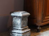 a marble pedestal on the floor next to a cabinet