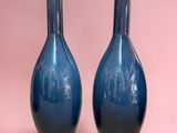 pair of blue vases on a pink background with a pink background