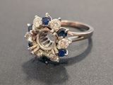 a close up of a diamond and sapphire ring on a table