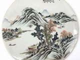 an image of a plate with a painting of mountains and trees