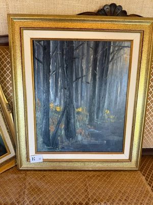 Deux tableaux encadrés représentant des arbres dans une forêt sont posés sur une table.