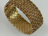 a close up of a gold bracelet on a white surface