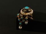 une image représentant une bague ornée de perles et de pierres de turquoise sur un fond noir