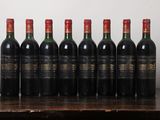 six bottles of red wine lined up on a wooden table