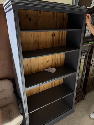 Quelqu'un est en train de peindre une bibliothèque dans un salon dont les murs sont recouverts de boiseries.