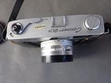 a silver camera sitting on a table with a black strap around it