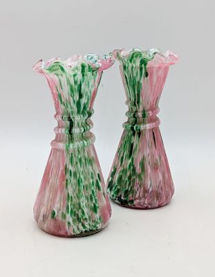 pair of pink and green glass vases on a white surface