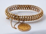 Gros plan sur un bracelet en or orné d'une pièce de monnaie