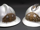 pair of white helmets with gold emblems on them on a black surface