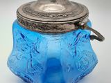bocal en verre bleu avec un couvercle argenté sur fond blanc