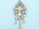 a silver and gold brooch on a blue surface