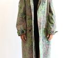 an image of a woman standing in front of a white wall wearing a green and black coat