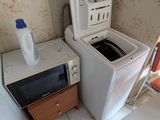 une photo d'une petite cuisine avec une machine à laver et un micro-ondes