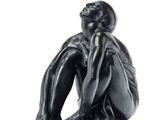 a black statue of a man sitting on a white surface