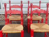 pair of red painted chairs with wicker seats