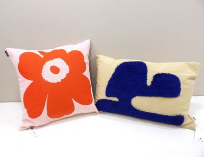 two pillows on a white table with a red and blue flower on it