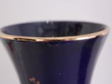a blue vase with a gold rim sitting on a table