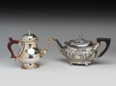 deux théières en argent et une théière en argent posées sur une table