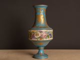 un vase bleu posé sur une table, sur fond noir