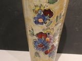 a vase with flowers painted on it sitting on a table