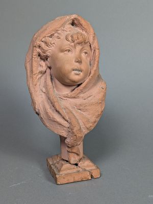 une photo d'une sculpture en argile représentant un enfant portant une écharpe