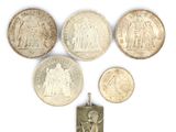six pièces d'argent et un pendentif en argent sur un fond blanc