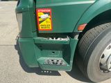 a green semi truck with a warning sign on the front
