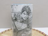 anime mug with a drawing of a man on it sitting on top of a basket