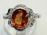 une image représentant une bague ornée d'une grosse pierre orange entourée de diamants