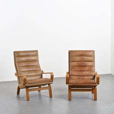 deux fauteuils en cuir marron dans une pièce aux murs blancs
