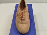 chaussures beiges à lacets posées sur une boîte bleue, sur une surface blanche